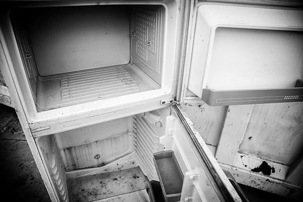 Broken refrigerator sitting outdoors