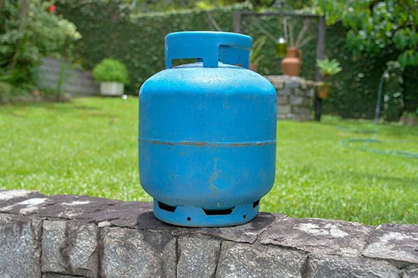 Propane tank sitting on landscape wall outdoors